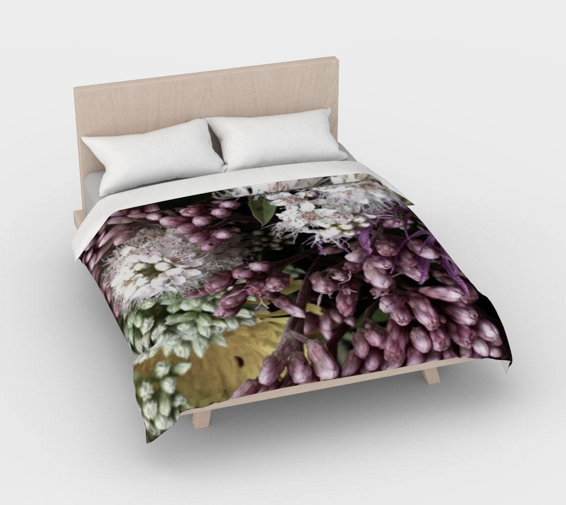 Bed of Flowers duvet cover by ZANA displayed on bed, featuring botanical art with purple hyacinth clusters, white starburst flowers, and pale green buds on black background